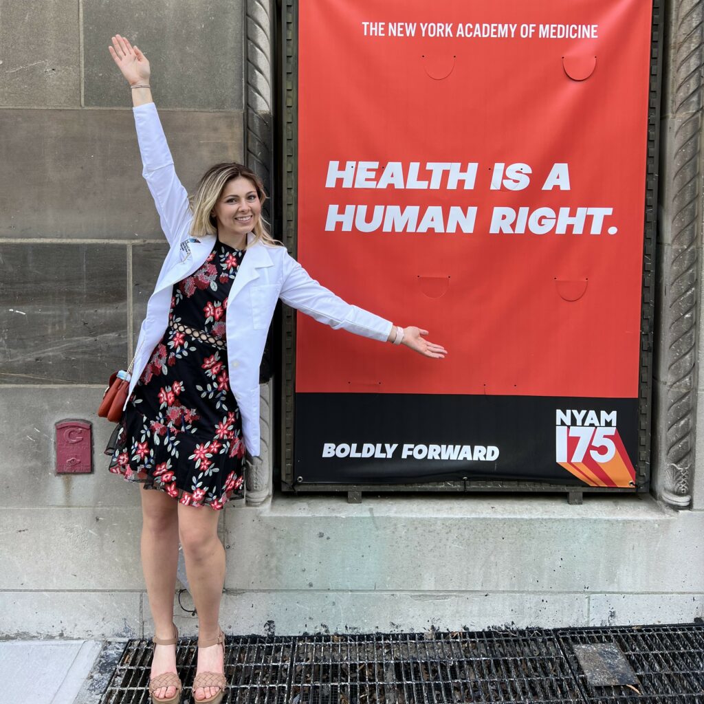 Adriana Pero standing in front of a sign that reads "Health is a human right"