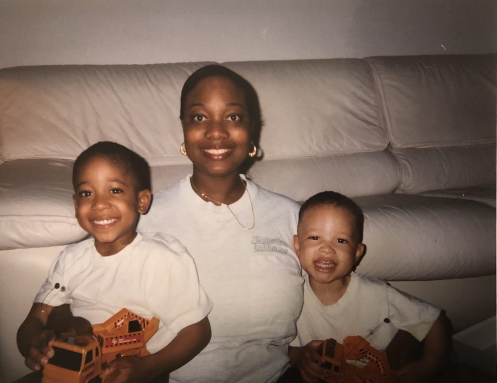 Makeen, his mom, and one other child sitting on the ground, smiling