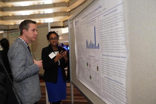 Two people stand, looking at a research poster