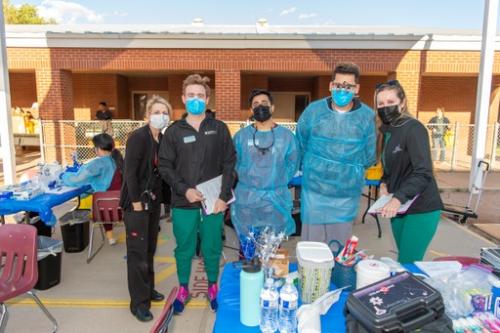 Healthcare workers pose for a photo at an elementary school, wearing surgical masks